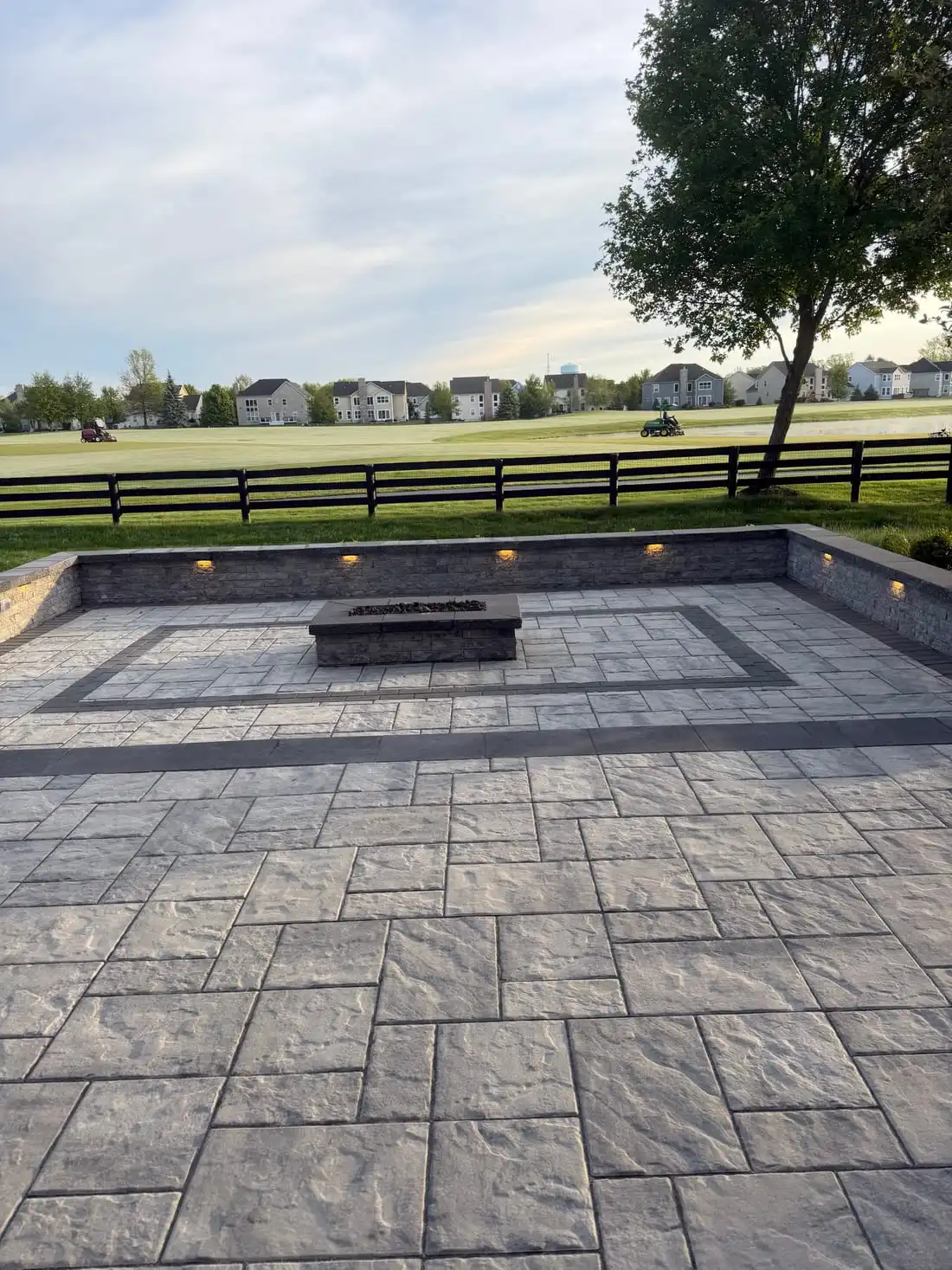 Paver patio with a curved seating wall and a built-in fire table