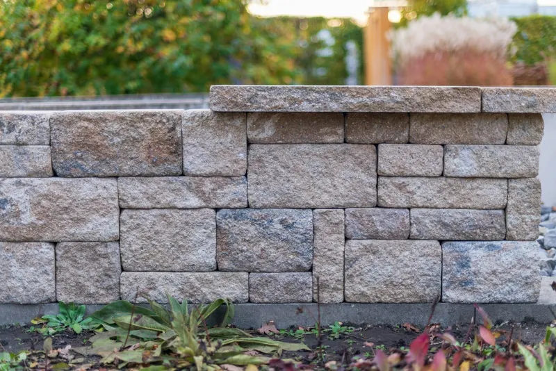 Stacked segmental block retaining wall with a capped top course
